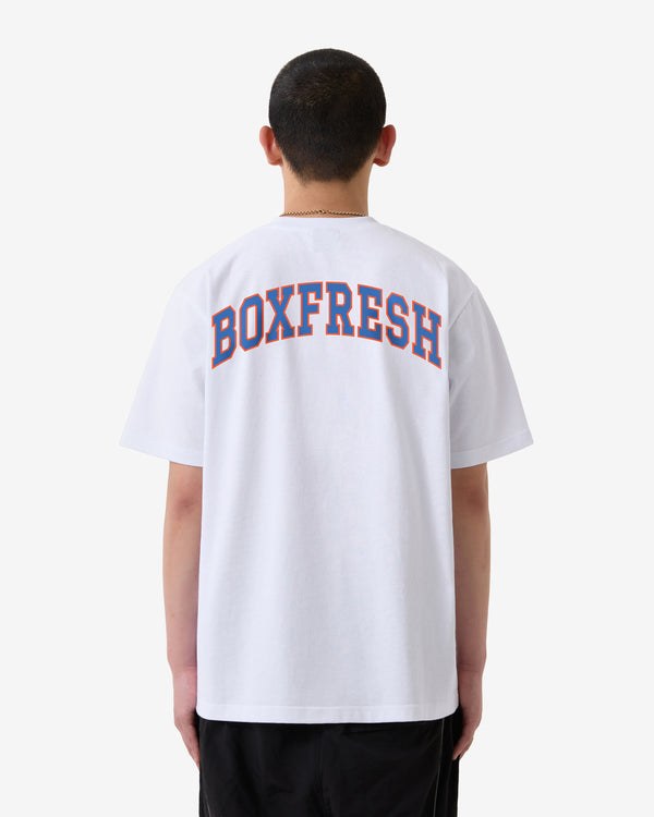 Person trägt ein weißes T-Shirt mit dem Aufdruck „BOXFRESH“ auf der Rückseite vor weißem Hintergrund