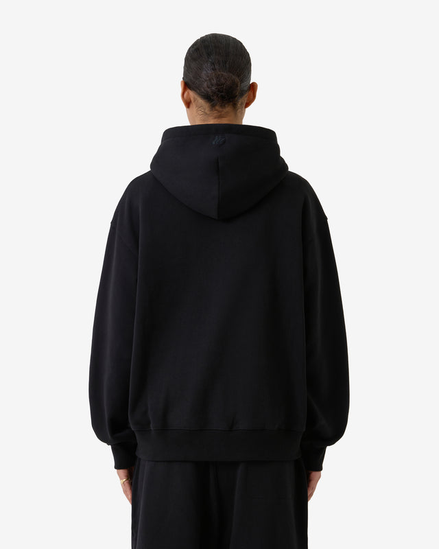 Back view of a model wearing a black hoodie. 