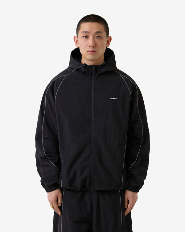 Person trägt eine schwarze Jacke mit einem Markenlogo auf weißem Hintergrund
