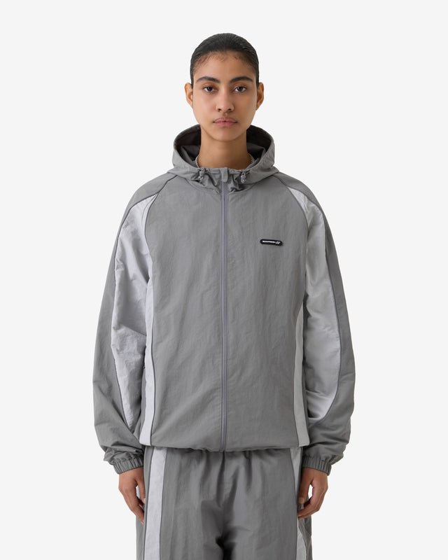 Person wearing a gray tracksuit with a brand logo on a white background