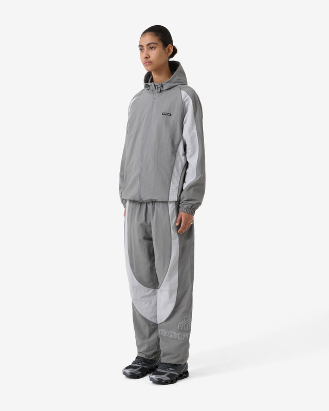 Person wearing a gray raincoat and pants on a white background