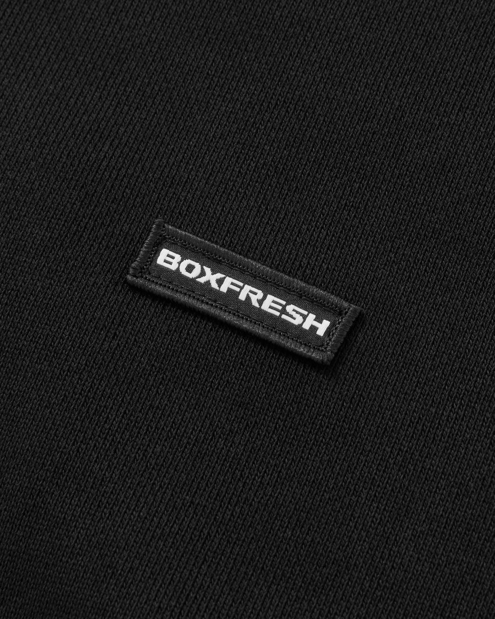Black sweatshirt with a small white logo on a light gray background