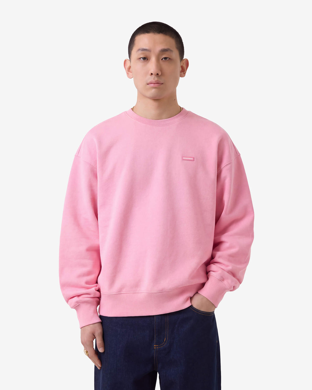Pink sweatshirt with a small logo on a light gray background