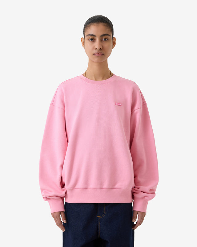 Front view of a model wearing a pink sweatshirt on a white background. 