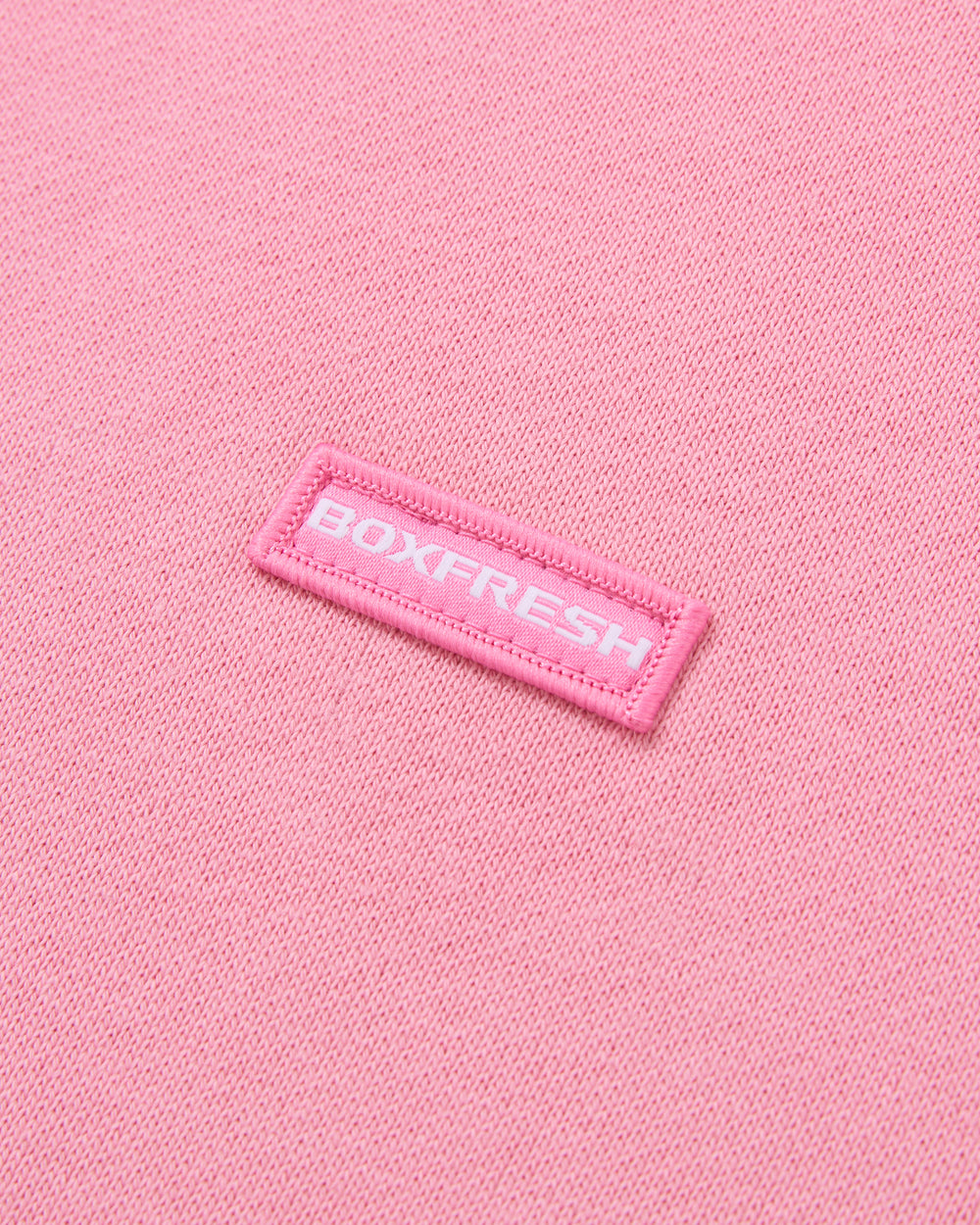 Pink sweatshirt with a small logo on a light gray background