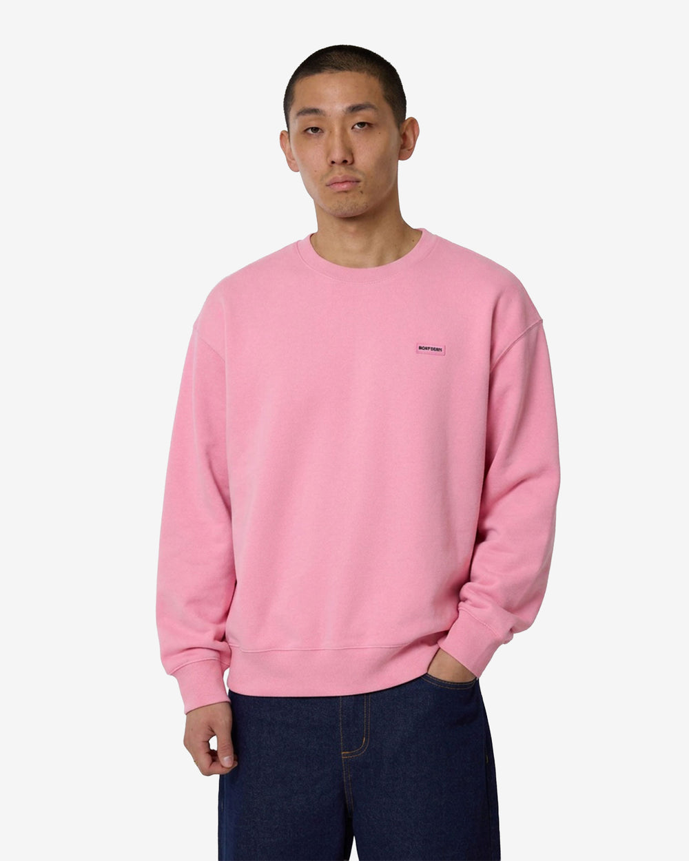 Pink sweatshirt with a small logo on a light gray background