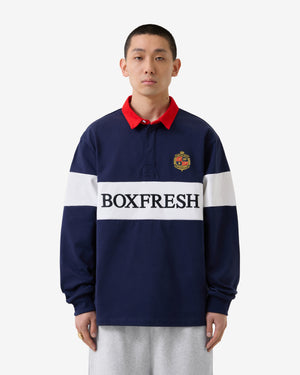 Person trägt ein dunkelblaues Rugby-Shirt mit rotem Kragen und „BOXFRESH“-Logo auf weißem Hintergrund