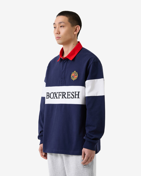 Person trägt ein dunkelblaues und rotes Langarmhemd mit „BOXFRESH“-Logo auf weißem Hintergrund