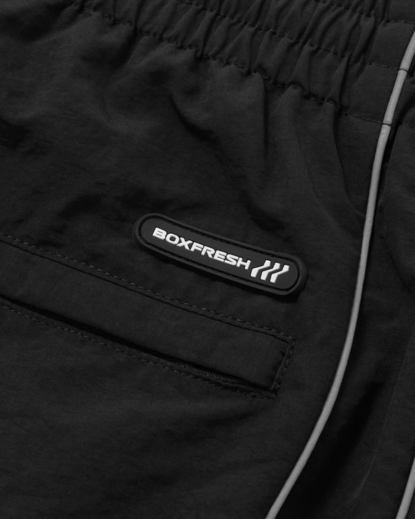 Schwarze Jacke mit sichtbarem Markenlogo auf dunklem Hintergrund
