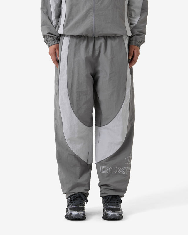 Person wearing a gray tracksuit with a visible brand logo on a white background
