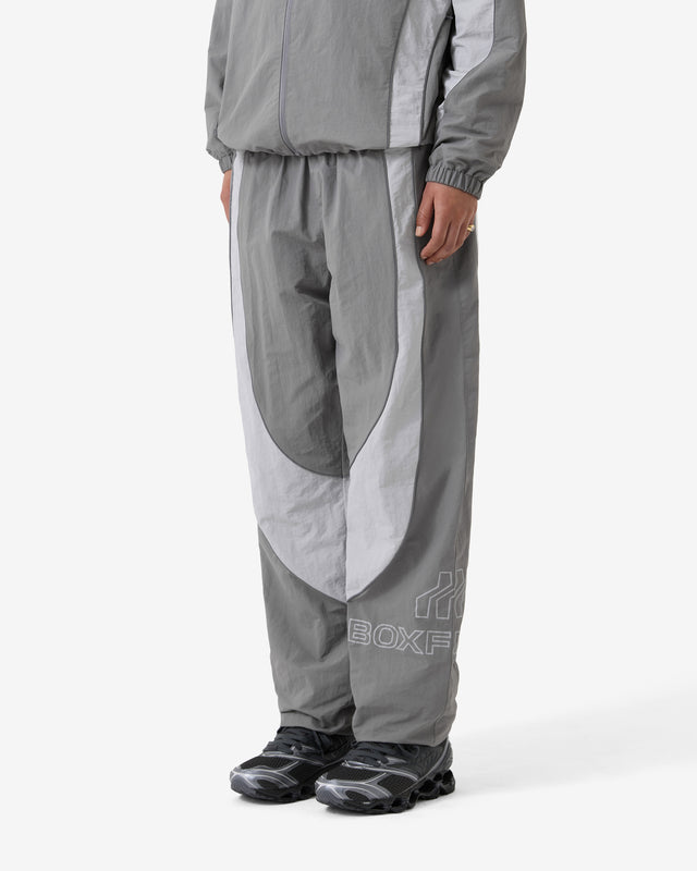 Person wearing a gray tracksuit with a brand logo on a white background