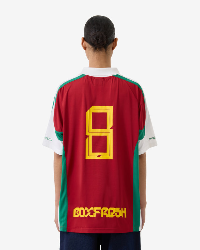Person wearing a red sports jersey with yellow and green accents, featuring the brand 'Boxfresh'.