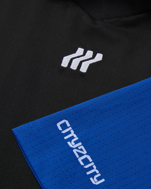 Nahaufnahme eines schwarz-blauen Kleidungsstücks mit Logo und Text.