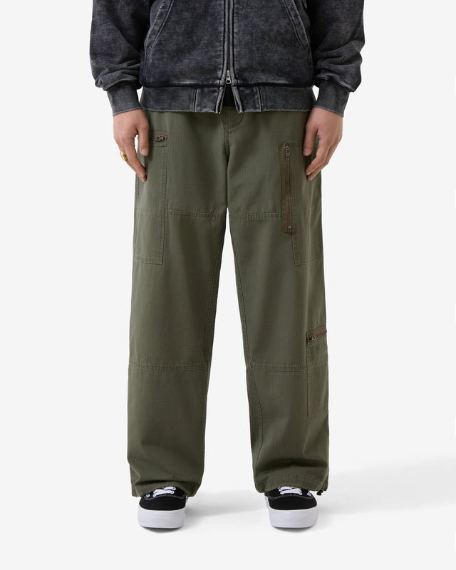 Person wearing olive green cargo pants with a dark jacket on a white background