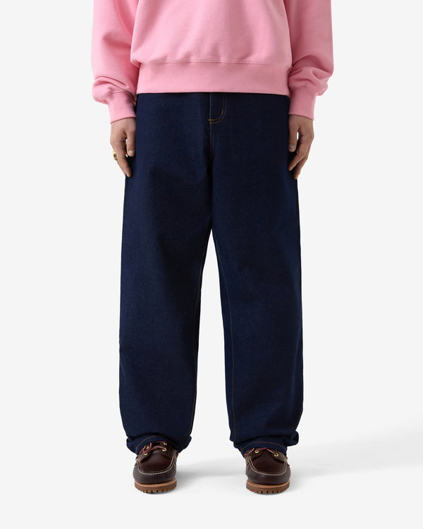 Person wearing a pink sweatshirt and navy pants on a white background