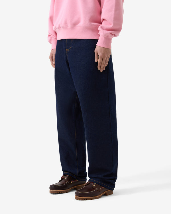 Person wearing a pink sweatshirt, navy pants, and brown shoes on a white background