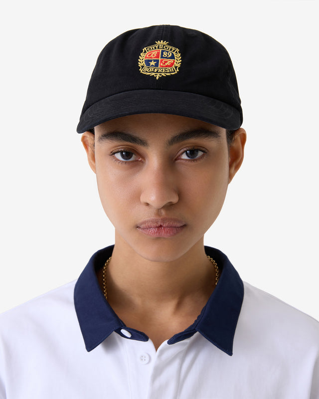 Person trägt eine schwarze Mütze mit Logo und ein weißes Hemd mit blauem Kragen.