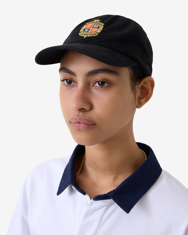Person trägt eine schwarze Mütze mit Logo und ein weißes Hemd mit blauem Kragen.